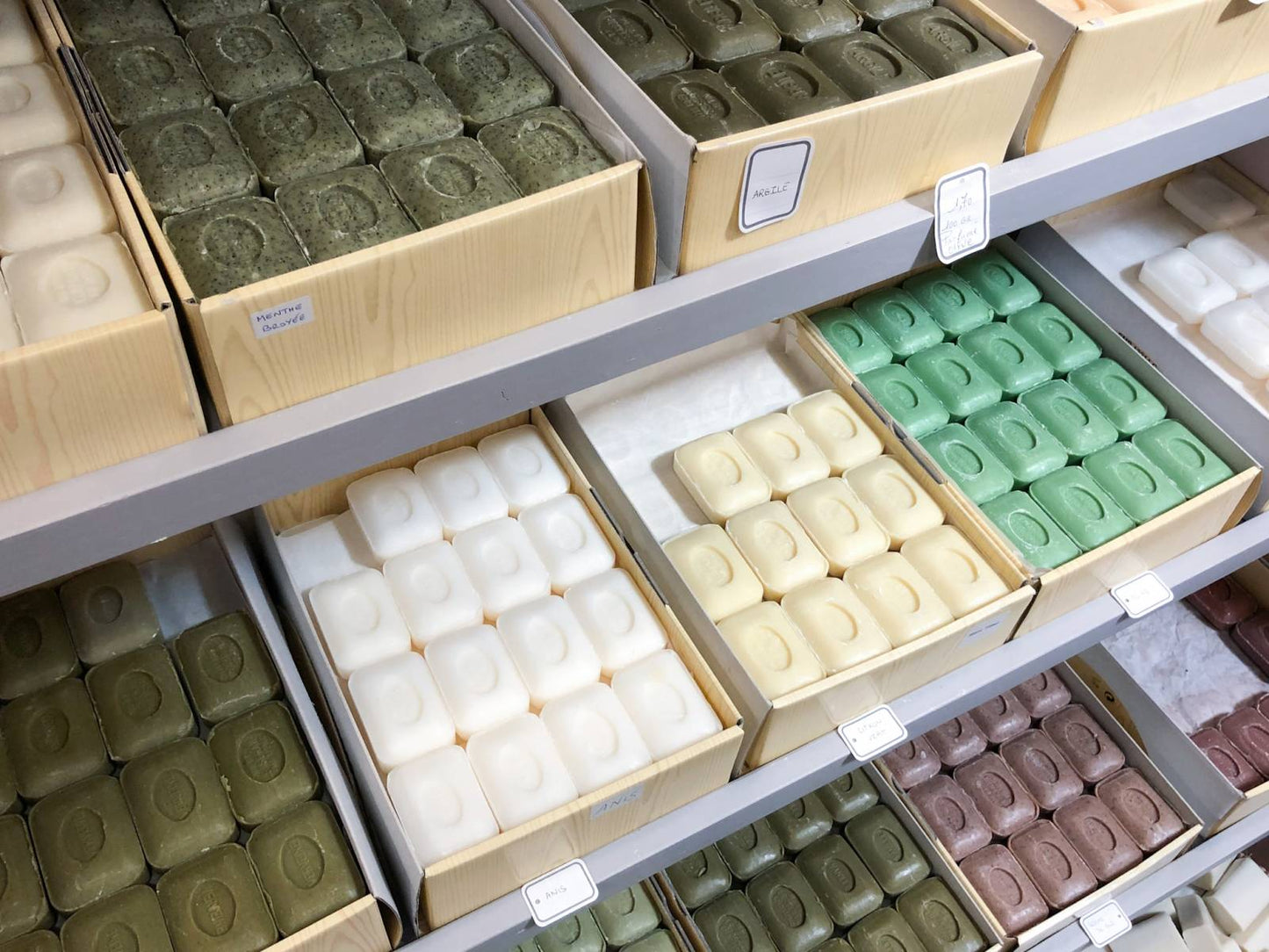 three shelves with bunch of different scented soaps are seen.